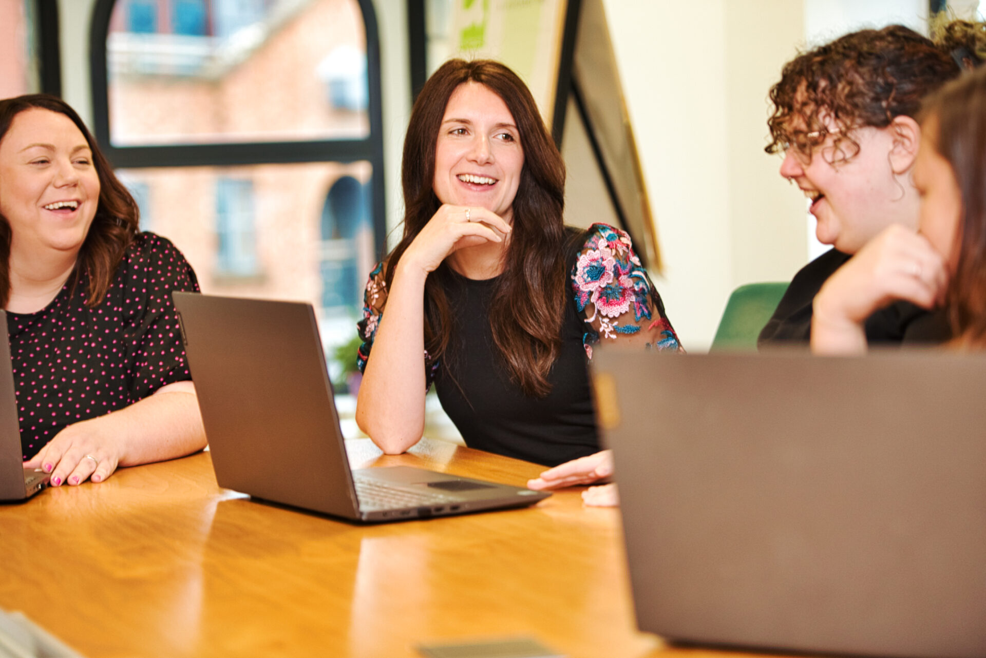 Smiling staff from Community Foundations for Lancashire and Merseyside with open laptops