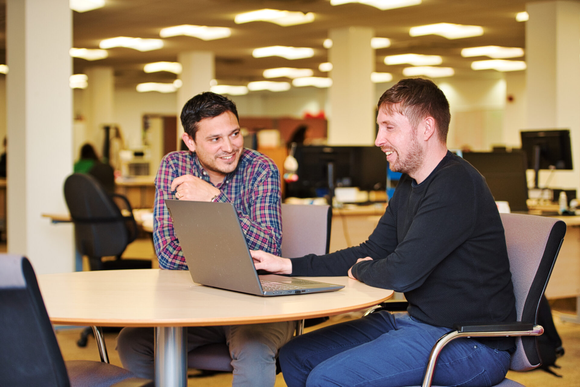 Two male staff from Community Foundations for Lancashire and Merseyside sitting at a table with a laptop