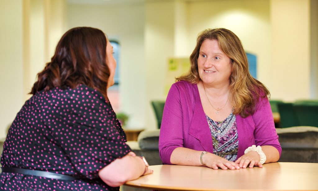 Two female staff members from Community Foundations for Lancashire and Merseyside sitting at a table and smiling