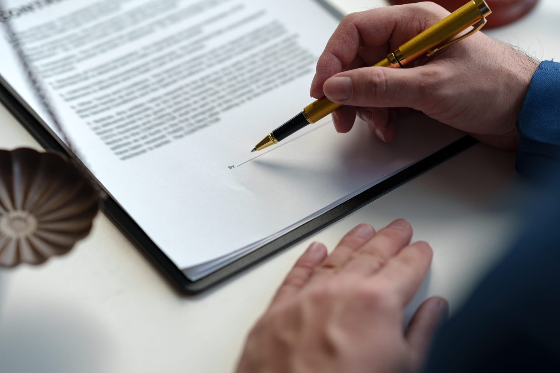 Person about to sign a document with a gold pen