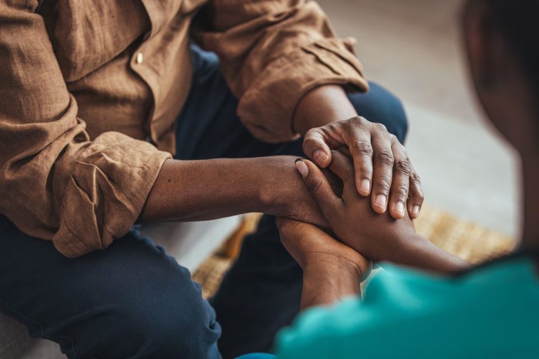 A close up of two people holding hands in a supportive way